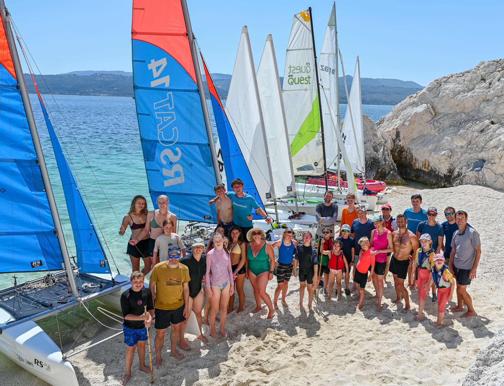Families on a beach in Greece with watersports and sailing