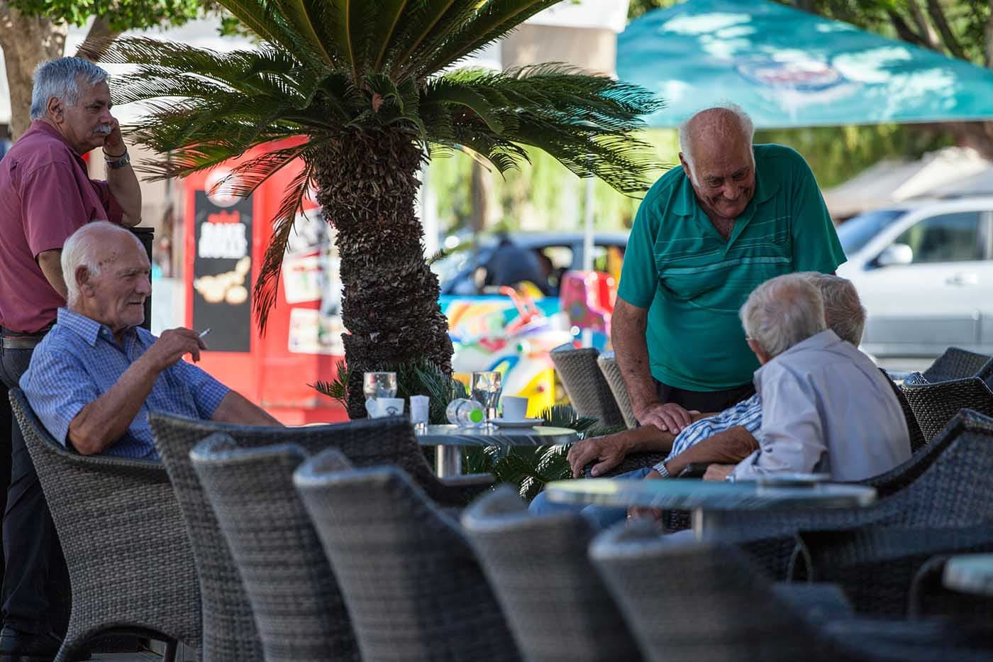 Locals in Lixouri town square by a bakery cafe